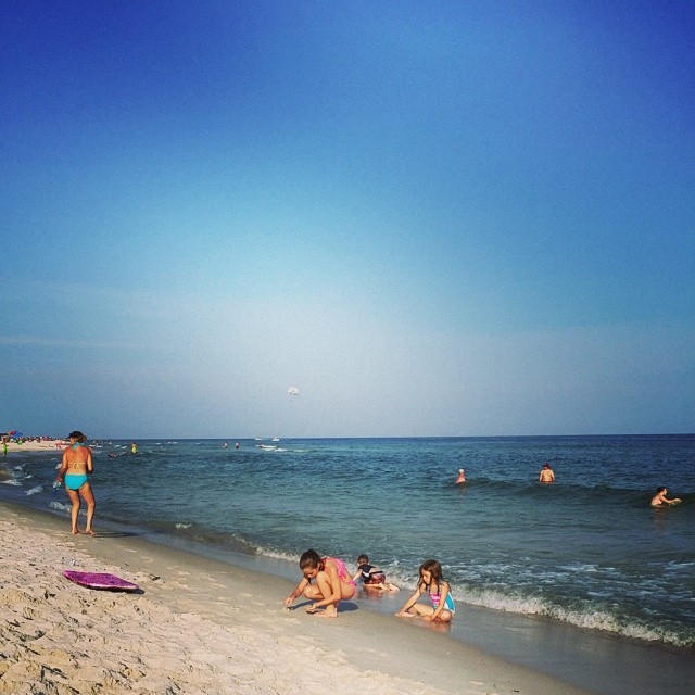 Kids playing on the beach while a parasailer gets reeled in in the background. #OrangeBeachCondo  #ParaSailing #gulfshores